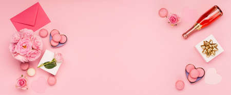 Festive holiday greeting card for Valentines, Birthday, Woman or Mothers Day. Flowers roses, gift box and sweets macaroons on pink background. Valentines day concept. Flat lay, top view, copy space.の写真素材