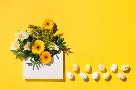 Festive holiday Easter flower composition. Yellow and white flowers, pastel easter eggs on paper...