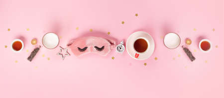 Sleeping mask, candle, lavender, herbal tea and alarm clock on pink pastel background. Quality of sleep, good night, insomnia, relaxation concept. Flat lay, top view. World Sleep day or week concept.の写真素材