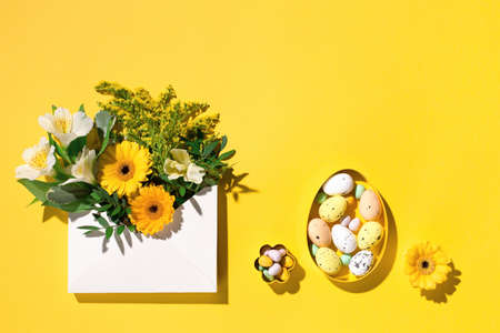 Festive holiday Easter flower composition. Yellow and white flowers, pastel easter eggs on paper...