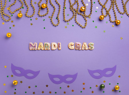 Mardi Gras King Cake cupcake or muffins, masquerade festival carnival mask, gold beads and golden, green confetti on purple background. Holiday party invitation, greeting card concept.の写真素材
