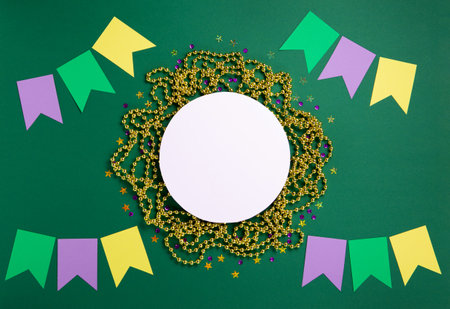 Mardi Gras masquerade festival carnival mask, gold beads and golden, green, purple confetti on green background. Holiday party invitation, greeting card concept. Top view, copy space.の写真素材