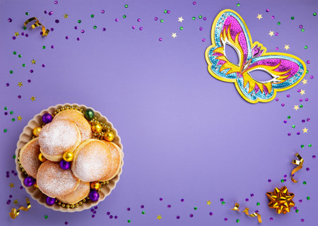 Mardi Gras King Cake donuts or donuts, masquerade festival carnival mask, gold beads and golden, green confetti on purple background. Holiday party invitation, greeting card concept.の写真素材
