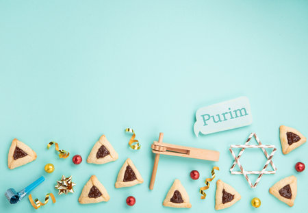 Purim celebration jewish holiday concept. Tasty hamantaschen cookies, Triangular pastry, Carnival mask, noisemaker, sweet candies and festive party decor on mint green background, Top view, copy spaceの写真素材
