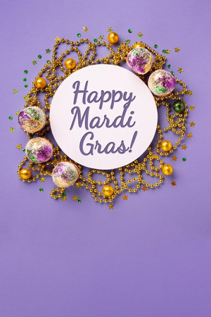 Mardi Gras King Cake cupcake or muffins, masquerade festival carnival mask, gold beads and golden, green confetti on purple background. Holiday party invitation, greeting card concept.の写真素材