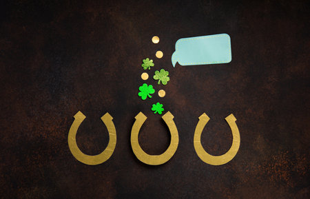 St. Patrick's Day celebration Concept. Greeting card with traditional symbols - Golden horseshoe, gold coins and clover leaves, green shamrocks on dark brown wooden background. Top view, copy space.の写真素材