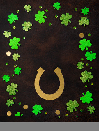 St. Patrick's Day celebration Concept. Greeting card with traditional symbols - Golden horseshoe, gold coins and clover leaves, green shamrocks on dark brown wooden background. Top view, copy space.の写真素材