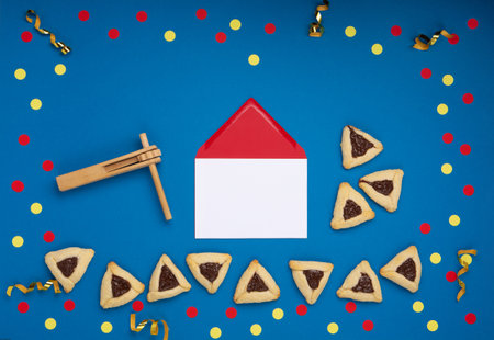 Homemade Purim hamantaschen cookies, Triangular pastry, Carnival mask, noisemaker, sweet candies and festive party decor on dark blue background, Top view. Purim celebration jewish holiday concept.の写真素材