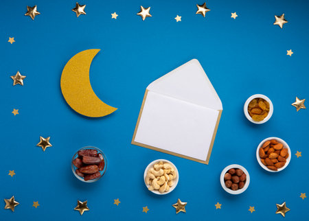 Ramadan Kareem concept. Date fruits, cashew nuts, almonds and crescent moon on blue background. Traditional Muslim Iftar Food. Top view, copy space.の写真素材