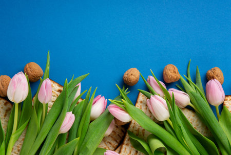 Jewish holiday Passover greeting card concept with matzah, nuts, tulip flowers on blue table Seder...