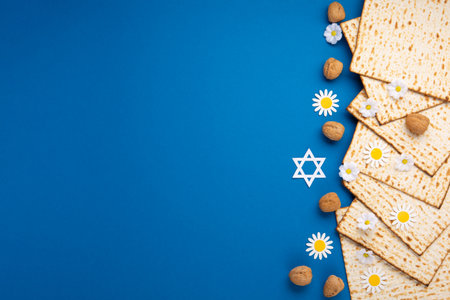 Jewish holiday Passover greeting card concept with matzah, nuts, spring flowers on blue table. Seder...