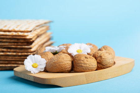 Jewish holiday Passover greeting card concept with matzah, nuts, spring daisy flowers on blue table....