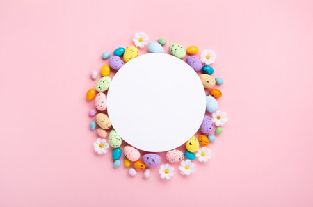 Sweet Colorful Easter Eggs and spring white daisy flowers on pastel pink background. Happy Easter greeting card concept. Flat lay, top view, copy space.の写真素材