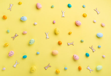 Sweet Colorful Easter Eggs and spring white daisy flowers on pastel yellow background. Happy Easter greeting card concept. Flat lay, top view, copy space.の写真素材