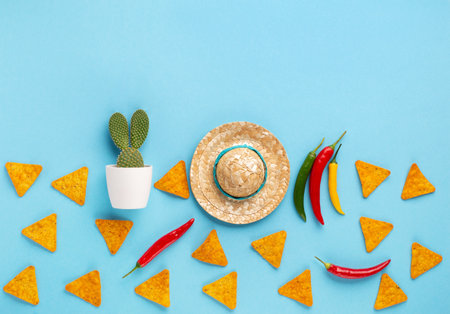 Mexican background fiesta with Traditional Mexican nachos chips, chilli pepper, cactus and sombrero hat on blue background. Cinco de Mayo (Fifth of May) celebration concept. Top view, copy space.の写真素材