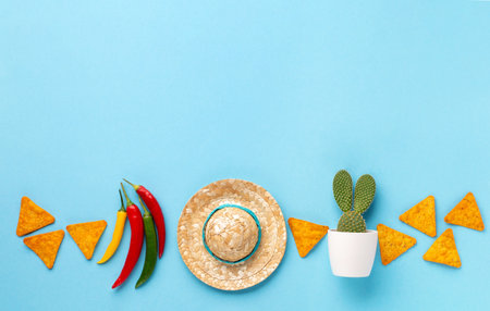 Mexican background fiesta with Traditional Mexican nachos chips, chilli pepper, cactus and sombrero hat on blue background. Cinco de Mayo (Fifth of May) celebration concept. Top view, copy space.の写真素材