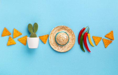 Mexican background fiesta with Traditional Mexican nachos chips, chilli pepper, cactus and sombrero hat on blue background. Cinco de Mayo (Fifth of May) celebration concept. Top view, copy space.の写真素材