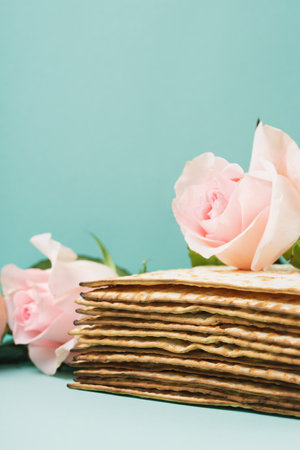 Jewish holiday Passover greeting card concept with matzah, Star of David, spring flowers, walnuts on blue mint table. Seder Pesach spring holiday background, copy space.の写真素材