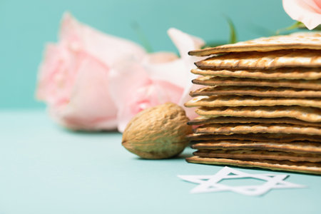 Seder Pesach spring holiday card. Jewish holiday Passover greeting card concept with matzah, Star of David, spring flowers, walnuts on blue mint background, copy space.の写真素材