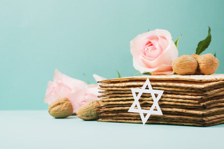 Jewish holiday Passover greeting card concept with matzah, Star of David, spring flowers, walnuts on blue mint table. Seder Pesach spring holiday background, copy space.の写真素材