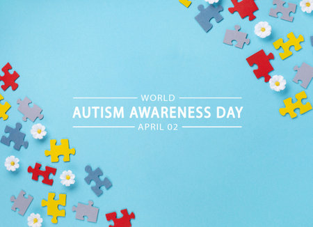 World Autism Awareness Day or month concept. Creative design for April 2. Color puzzle, symbol of awareness for autism spectrum disorder and daisy flowers on blue background. Top view, copy space for text.の写真素材