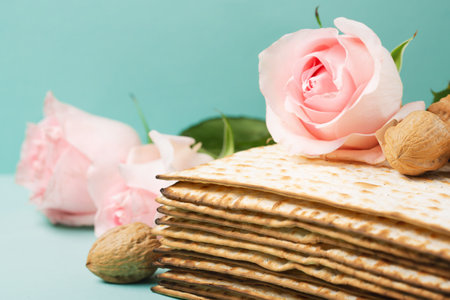 Jewish holiday Passover greeting card concept with matzah, Star of David, spring flowers, walnuts on blue mint table. Seder Pesach spring holiday background, copy space.の写真素材
