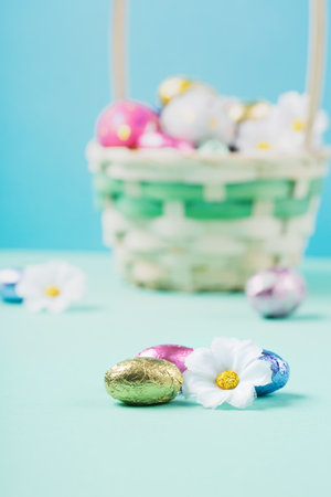 Easter Basket, Sweet Colorful Chocolate Easter Eggs, daisy flowers on pastel blue mint background....