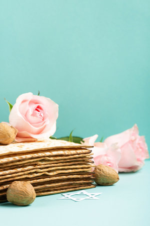Jewish holiday Passover greeting card concept with matzah, Star of David, spring flowers, walnuts on blue mint table. Seder Pesach spring holiday background, copy space.の写真素材