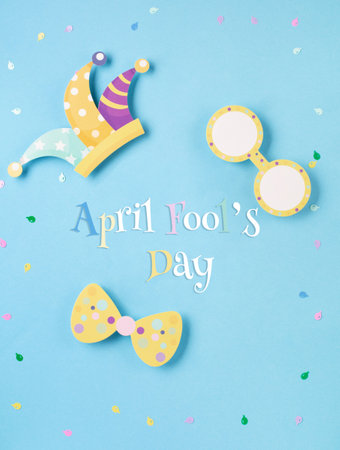 April Fool's Day holiday card with Jester hat, confetti and funny glasses on blue background, top view. International Day of Laughter. Concept for greeting cards, banners, flyers.の写真素材