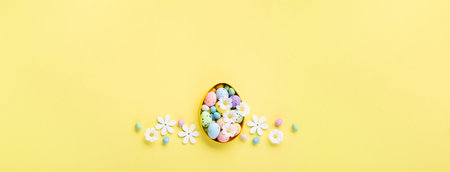 Sweet Colorful Easter Eggs and spring white daisy flowers on pastel yellow background. Happy Easter greeting card concept. Flat lay, top view, copy space.の写真素材