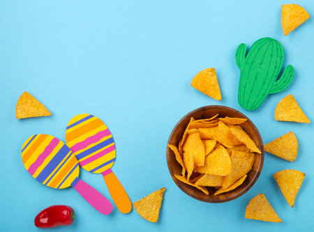 Mexican background fiesta with Traditional Mexican nachos chips, red chilli pepper, cactus and maracas on blue background. Cinco de Mayo (Fifth of May) celebration concept. Top view, copy space.の写真素材