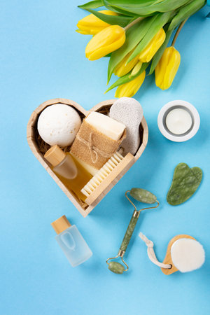 Natural eco friendly beauty skin care products, spa accessories for women and spring tulip flowers on blue background. Zero waste self care heart shape gift box for Mothers day, womans day, birthday.の写真素材