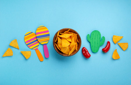 Mexican background fiesta with Traditional Mexican nachos chips, red chilli pepper, cactus and maracas on blue background. Cinco de Mayo (Fifth of May) celebration concept. Top view, copy space.の写真素材