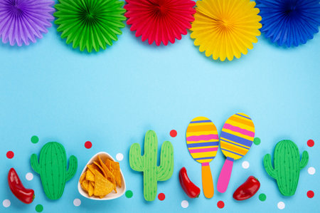 Mexican background fiesta with Traditional Mexican nachos chips, red chilli pepper, cactus and maracas on blue background. Cinco de Mayo (Fifth of May) celebration concept. Top view, copy space.の写真素材