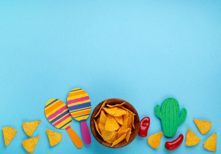 Mexican background fiesta with Traditional Mexican nachos chips, red chilli pepper, cactus and maracas on blue background. Cinco de Mayo (Fifth of May) celebration concept. Top view, copy space.の写真素材