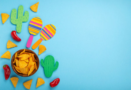 Mexican background fiesta with Traditional Mexican nachos chips, red chilli pepper, cactus and maracas on blue background. Cinco de Mayo (Fifth of May) celebration concept. Top view, copy space.の写真素材