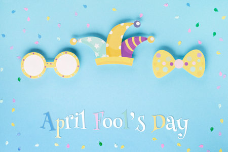 April Fool's Day holiday card with Jester hat, confetti and funny glasses on blue background, top view. International Day of Laughter. Concept for greeting cards, banners, flyers.の写真素材