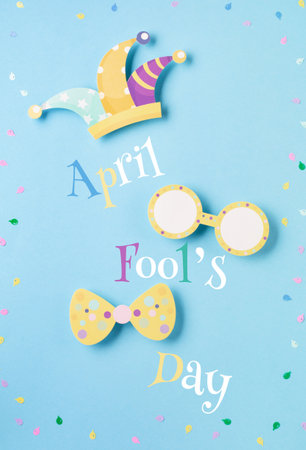 April Fool's Day holiday card with Jester hat, confetti and funny glasses on blue background, top view. International Day of Laughter. Concept for greeting cards, banners, flyers.の写真素材