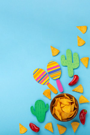 Mexican background fiesta with Traditional Mexican nachos chips, red chilli pepper, cactus and maracas on blue background. Cinco de Mayo (Fifth of May) celebration concept. Top view, copy space.の写真素材