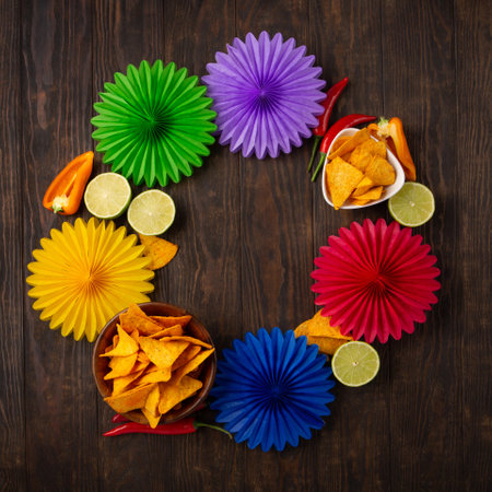 Cinco de Mayo (Fifth of May) celebration concept. Mexican background fiesta with Traditional Mexican nachos chips, red chili peppers, green lime on dark wooden background. Top view, copy space.の写真素材