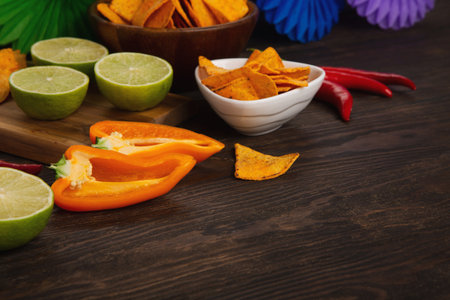 Cinco de Mayo (Fifth of May) celebration concept. Mexican background fiesta with Traditional Mexican nachos chips, red chili peppers, green lime on dark wooden background. Top view, copy space.の写真素材