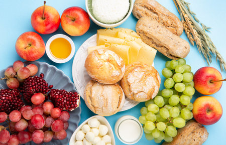 Happy Shavuot holiday card. Jewish religious holiday concept. Dairy products, grapes, cheese, bread, milk, cottage cheese, wheat, honey on blue background. top view.の写真素材