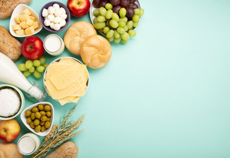 Happy Shavuot holiday card. Jewish religious holiday concept. Dairy products, fruits, cheese, bread, milk bottle, cottage cheese, wheat on blue mint background. Top view, copy space.の写真素材