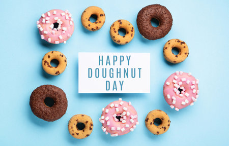 Donuts donuts with chocolate, marshmallow and sugar sprinkles on blue background, copy space. Colorful carnival or birthday party card. Happy National donut day Concept.の写真素材