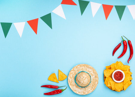 Mexican fiesta background with Traditional Mexican nachos chips, chilli peppers and tomato salsa sauce on blue table. Cinco de Mayo (Fifth of May) celebration concept. Top view, copy space.の写真素材