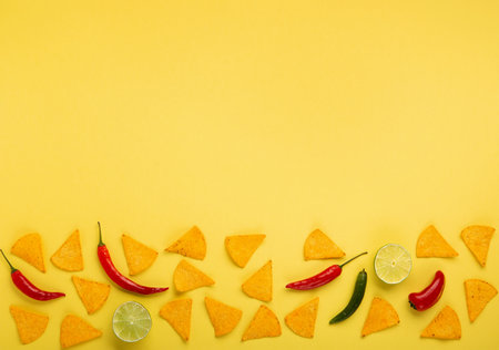 Mexican fiesta background with Traditional Mexican nachos chips, chilli peppers and tomato salsa sauce on yellow background. Cinco de Mayo (Fifth of May) celebration concept. Top view, copy space.の写真素材