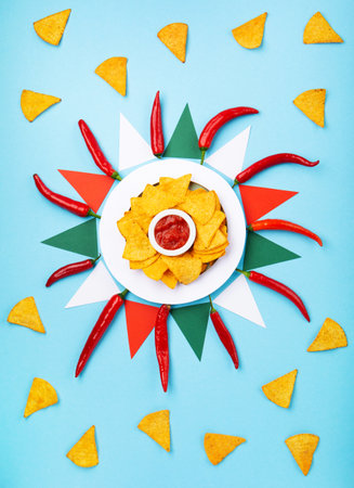 Mexican fiesta background with Traditional Mexican nachos chips, chilli peppers and tomato salsa sauce on blue table. Cinco de Mayo (Fifth of May) celebration concept. Top view, copy space.の写真素材