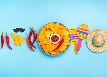 Mexican fiesta background with Traditional Mexican nachos chips, chilli peppers and tomato salsa sauce on blue table. Cinco de Mayo (Fifth of May) celebration concept. Top view, copy space.の写真素材
