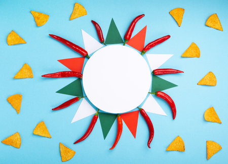 Mexican fiesta background with Traditional Mexican nachos chips, chilli peppers and tomato salsa sauce on blue table. Cinco de Mayo (Fifth of May) celebration concept. Top view, copy space.の写真素材