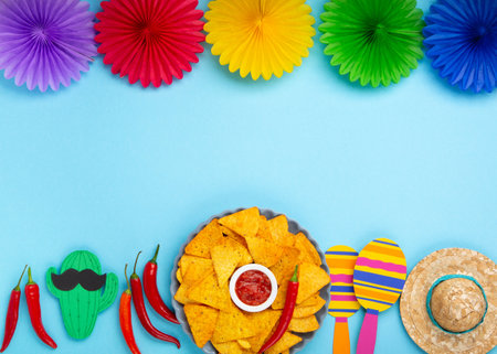 Mexican fiesta background with Traditional Mexican nachos chips, chilli peppers and tomato salsa sauce on blue table. Cinco de Mayo (Fifth of May) celebration concept. Top view, copy space.の写真素材